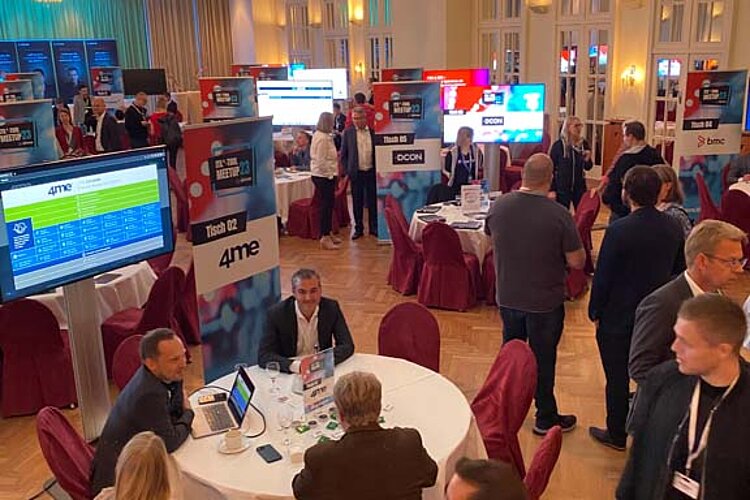 Teilnehmer des SERVIEW TOOL MEETUP sitzen an runden Tischen in einem eleganten Saal mit Kronleuchtern und LED-Deckenbeleuchtung und diskutieren mit Ausstellern.