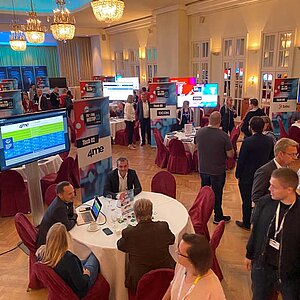 Teilnehmer des SERVIEW TOOL MEETUP sitzen an runden Tischen in einem eleganten Saal mit Kronleuchtern und LED-Deckenbeleuchtung und diskutieren mit Ausstellern.