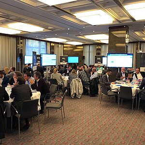 Teilnehmer des ITSM-Tool MeetUp18 sitzen an runden Tischen in einem modernen Konferenzraum und diskutieren mit Experten über IT-Lösungen.