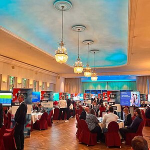 Teilnehmer des SERVIEW TOOL MEETUP sitzen an runden Tischen in einem eleganten Saal mit Kronleuchtern und LED-Deckenbeleuchtung und diskutieren mit Ausstellern.