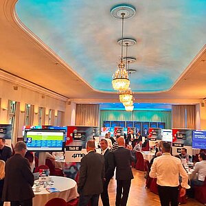 Teilnehmer des SERVIEW TOOL MEETUP sitzen an runden Tischen in einem eleganten Saal mit Kronleuchtern und LED-Deckenbeleuchtung und diskutieren mit Ausstellern.