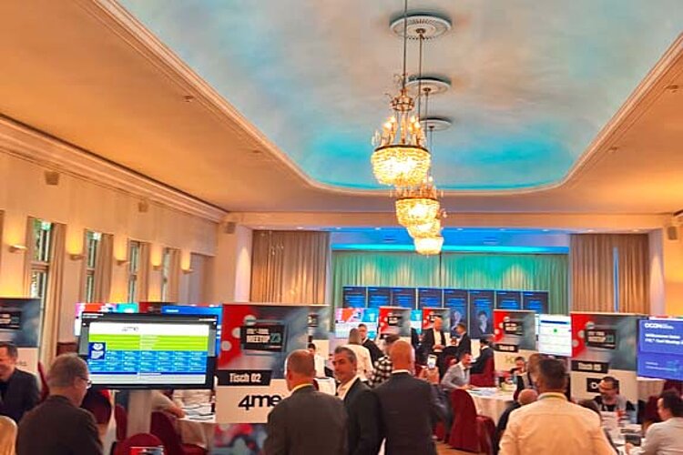 Teilnehmer des SERVIEW TOOL MEETUP sitzen an runden Tischen in einem eleganten Saal mit Kronleuchtern und LED-Deckenbeleuchtung und diskutieren mit Ausstellern.