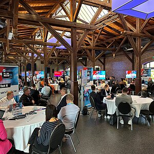 Teilnehmer des SERVIEW TOOL MEETUP23 in einer rustikalen Event-Location mit Holzbalken und Backsteinwänden, die an runden Tischen diskutieren.